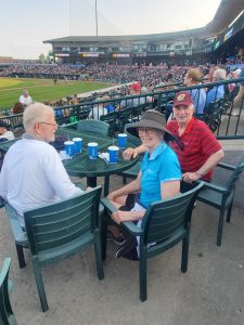 Congregation members at a table at the Loons game, with the playing field in the background.